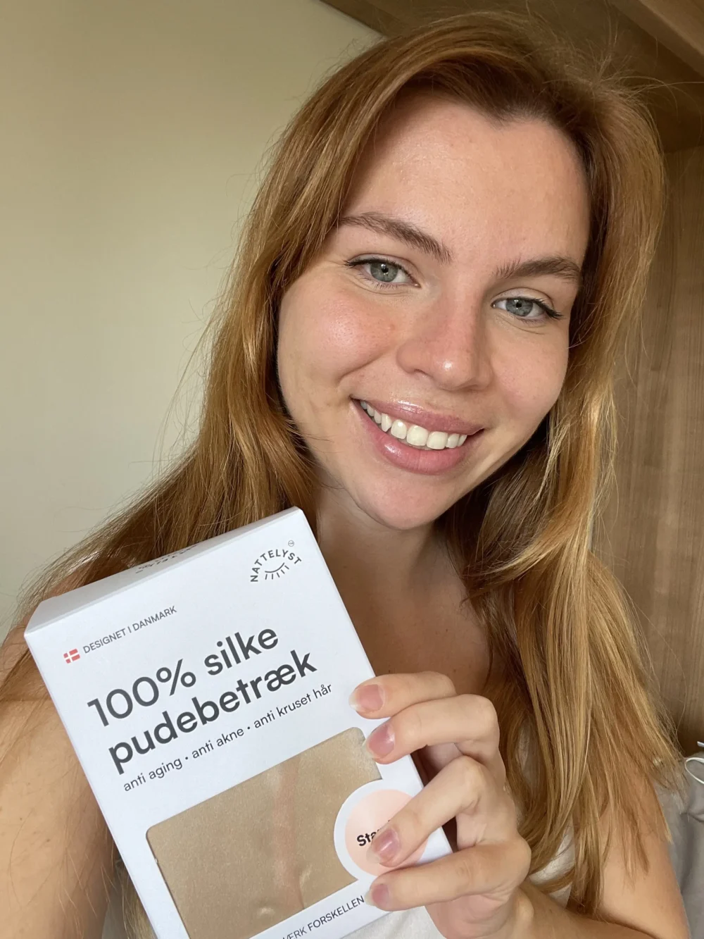 Smilende kvinde holder æske med 100% silke pudebetræk