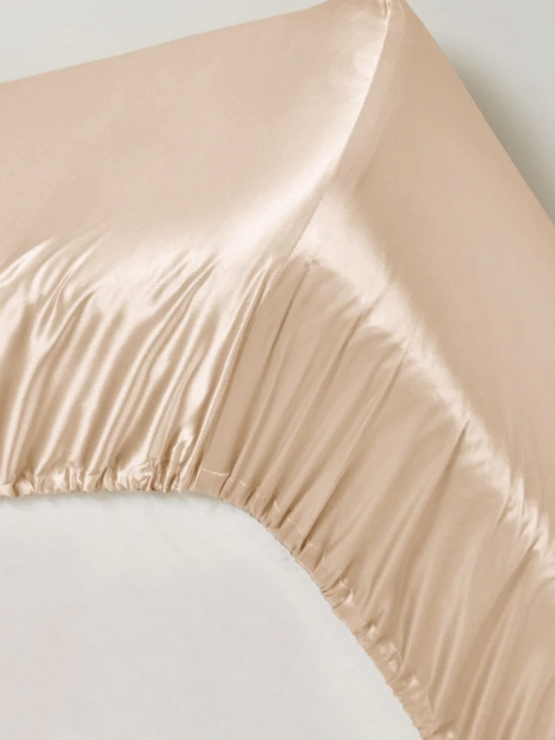 Champagnefarvet satin stræklagen med elastisk kant på madras